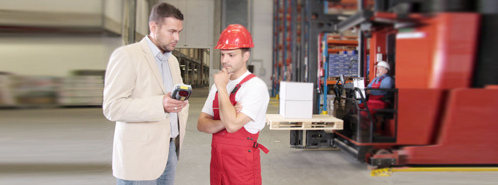Ein Steuerberater unterhält sich in einer Produktionshalle mit einem Unternehmer über Betriebswirtschaftliche Beratung.